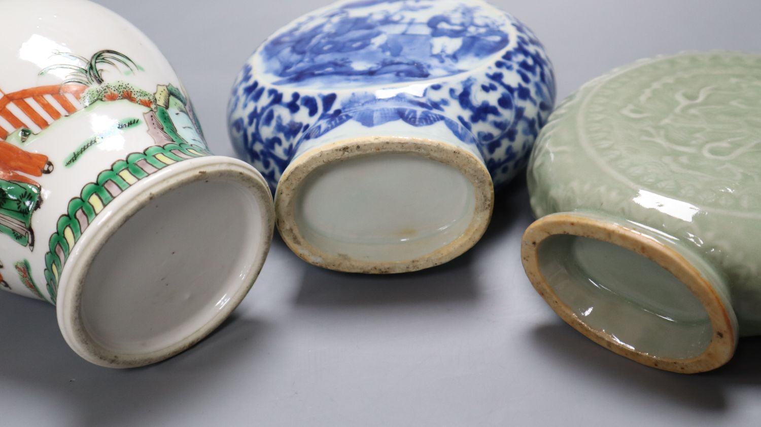 A Chinese blue and white moon flask, a Chinese celadon glazed moon flask and a famille verte baluster vase, tallest 21cm